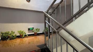 A staircase with metal railings, a digital clock, and potted plants on a counter.