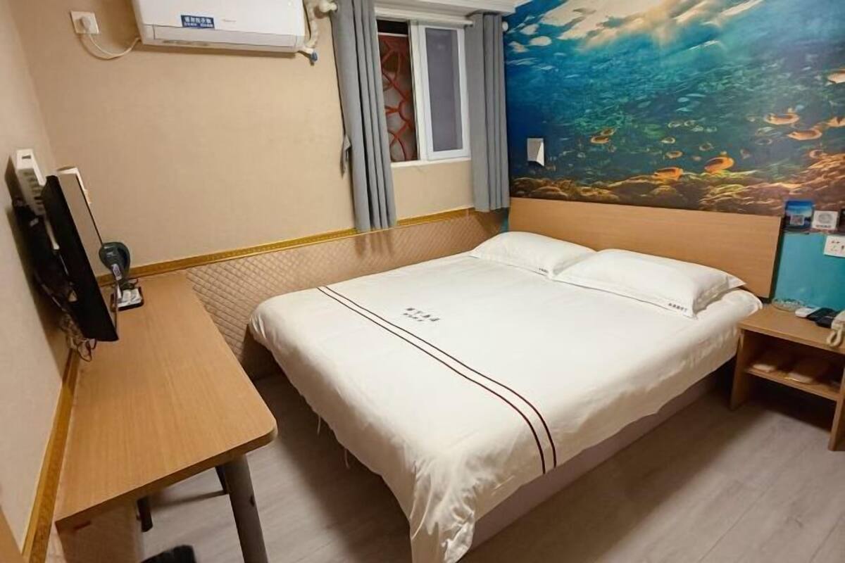 Habitació d'hotel amb un llit, escriptori, telèfon i finestra amb cortines.