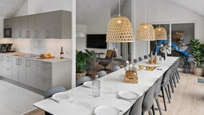 A modern kitchen with grey cabinets, a dining area with a long table set for six, and a large window overlooking a garden. - 5 Star Holiday Home in Lokken (Lokken)