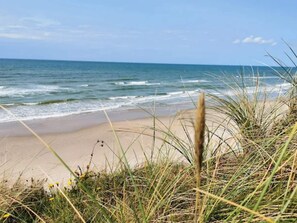 A beach with waves, sand, and grass. - 5 Star Holiday Home in Lokken (Lokken)