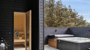 A wooden cabin with a sauna room, a hot tub, and a grill outside. - 5 Star Holiday Home in Lokken (Lokken)