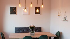 A dining area with a wooden table, green upholstered chairs, and pendant lights. - Apartment in the heart of Braunschweig (Braunschweig)