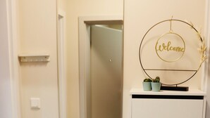 A hallway with a white door, a mirror, a welcome sign, and a small potted plant. - Apartment in the heart of Braunschweig (Braunschweig)