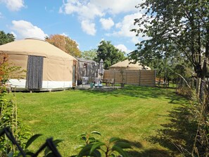 A campsite with a large tent, a wooden structure, and a fenced area.