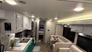 A compact RV interior with a kitchenette, a dining area, and a seating space. - Hillside Haven in Berryessa (San Jose)