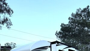 A white RV with a large awning, parked on gravel. - Hillside Haven in Berryessa (San Jose)