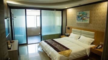 Habitación de hotel con una cama grande, una mesita de noche, un teléfono en la pared y una puerta corrediza de vidrio que da a un balcón.
