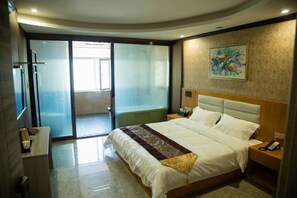 Habitación de hotel con una cama grande, una mesita de noche, un teléfono en la pared y una puerta corrediza de vidrio que da a un balcón.