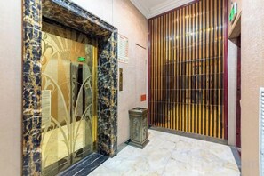 An elevator with a glass door and a marble floor. - Lanzhou Huayu Business Hotel (Lanzhou)