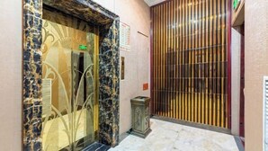 Un ascensor con detalles de mármol y un panel de vidrio decorativo.