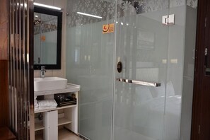 Un baño moderno con cabina de ducha de vidrio, un lavabo blanco y un espejo.