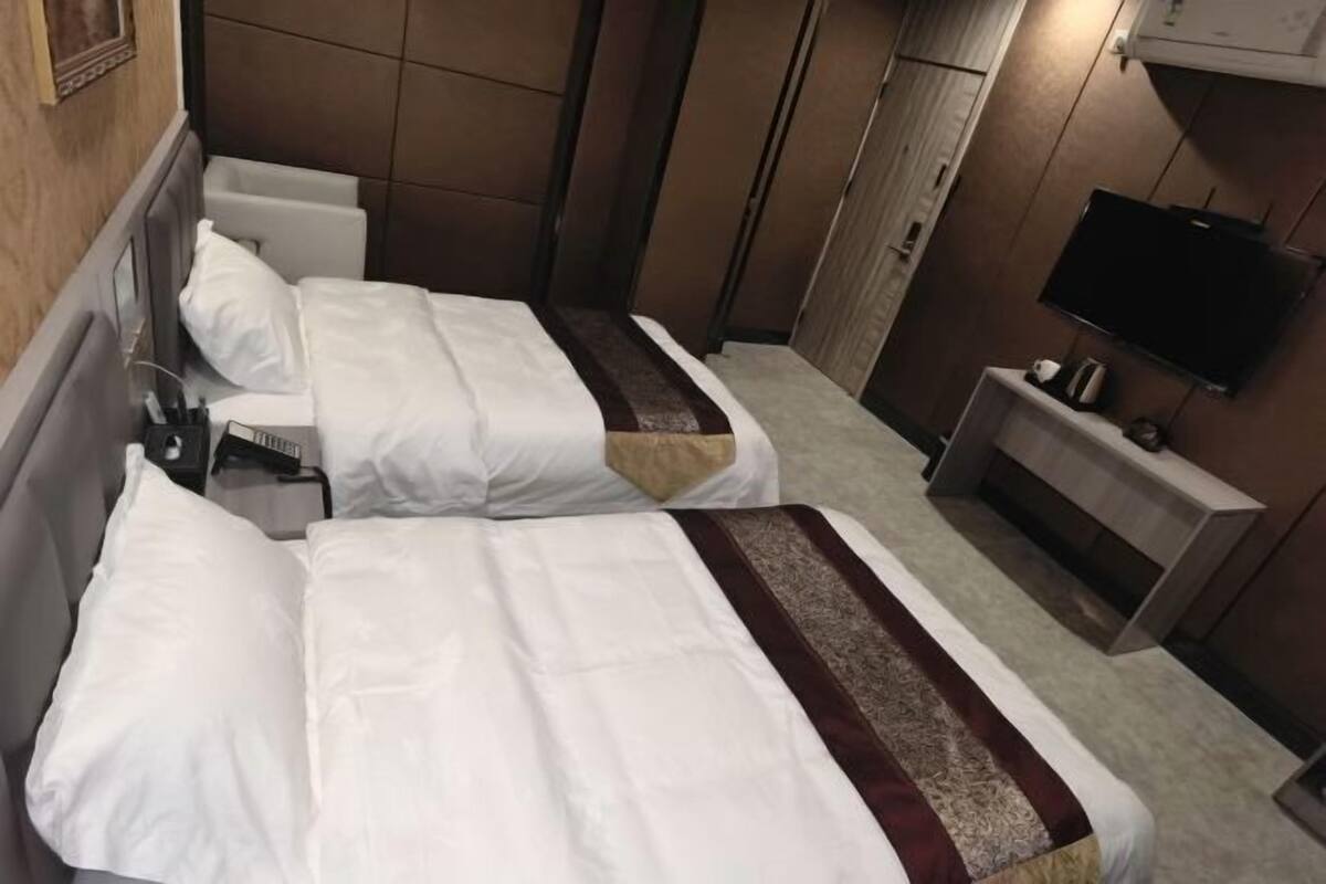 Een hotelkamer met twee bedden, een televisie en een zithoek.