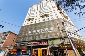 Un edificio de varios pisos con un letrero que dice 'Flower Rain Business Hotel' en la parte superior.