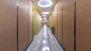 Un pasillo largo y estrecho con piso de mármol pulido e iluminación empotrada.
