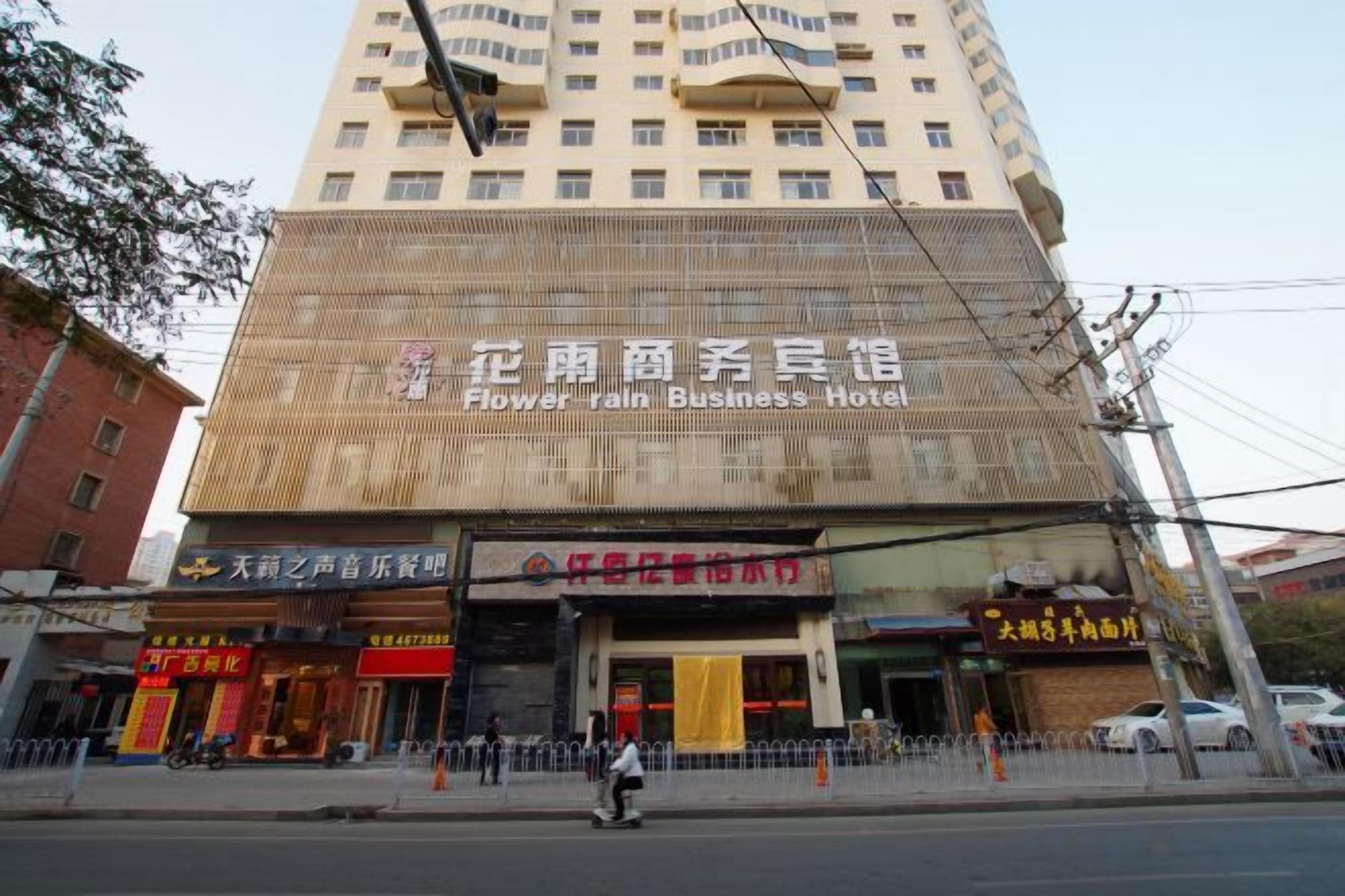 A multi-story building with a sign for 'Flower Rain Business Hotel'.