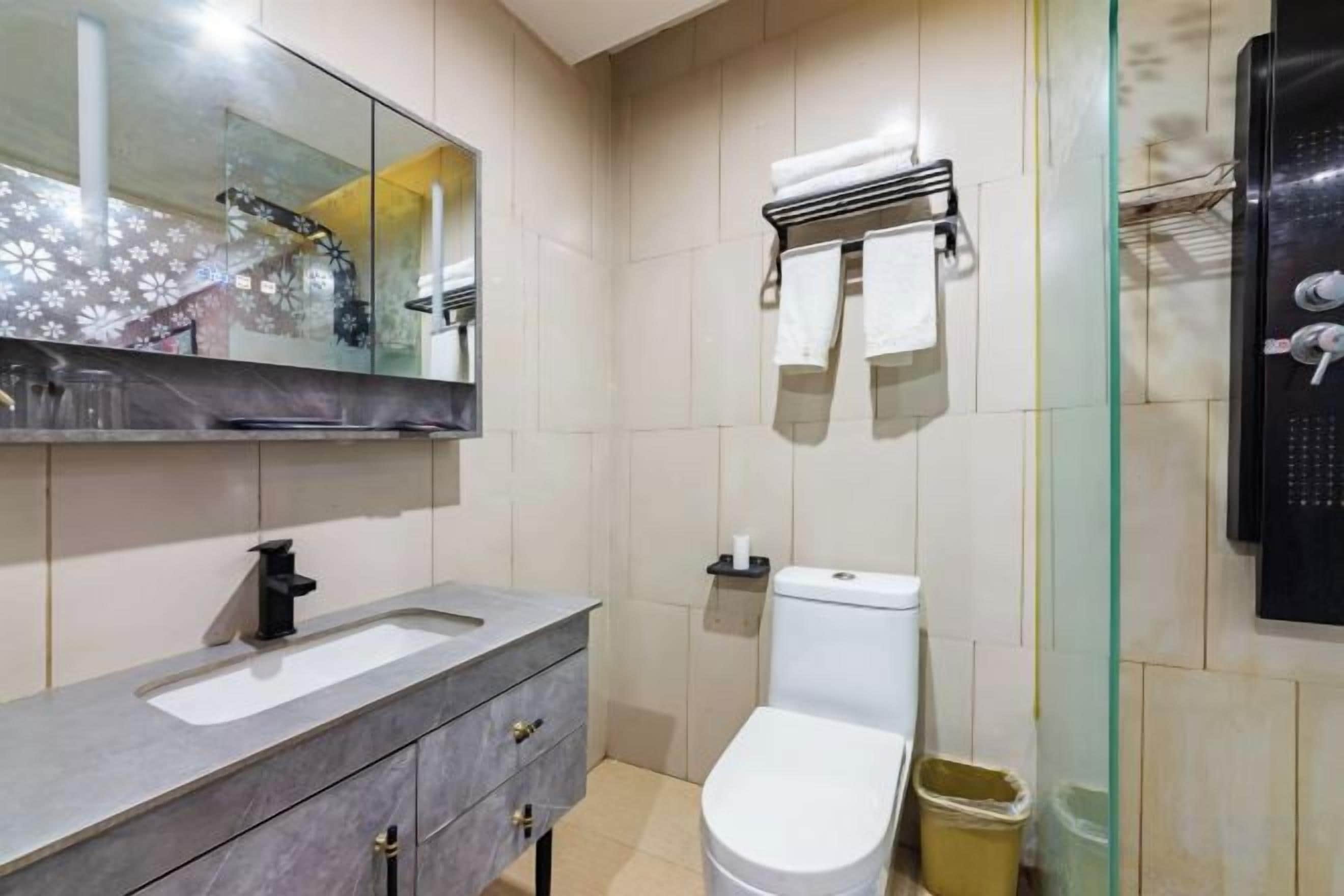 Ein Badezimmer mit einer weißen Toilette, einem Waschbecken mit Spiegel und einer Duschkabine aus Glas.
