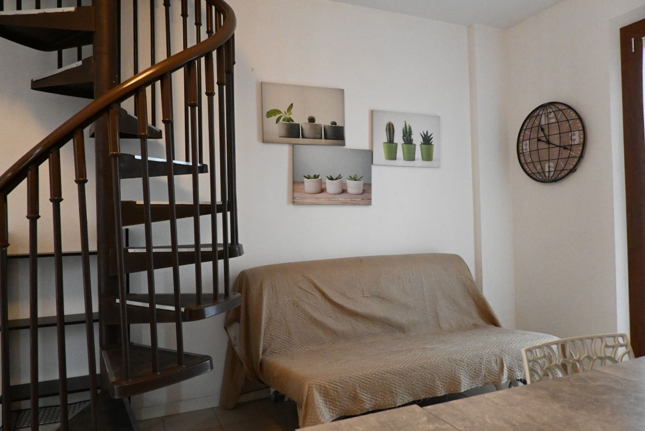 A bedroom with a covered bed, a wooden staircase, and wall-mounted potted plants.