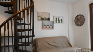 Ein Schlafzimmer mit einem bezogenen Bett, einer Holztreppe und an der Wand befestigten Blumentöpfen.