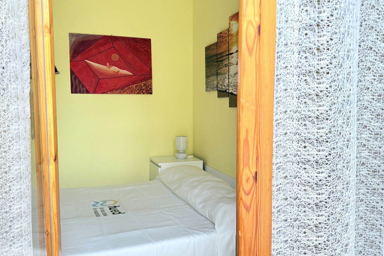 Ein Zimmer mit einem Bett, einem Nachttisch mit einer Lampe und einem Bild an der Wand.