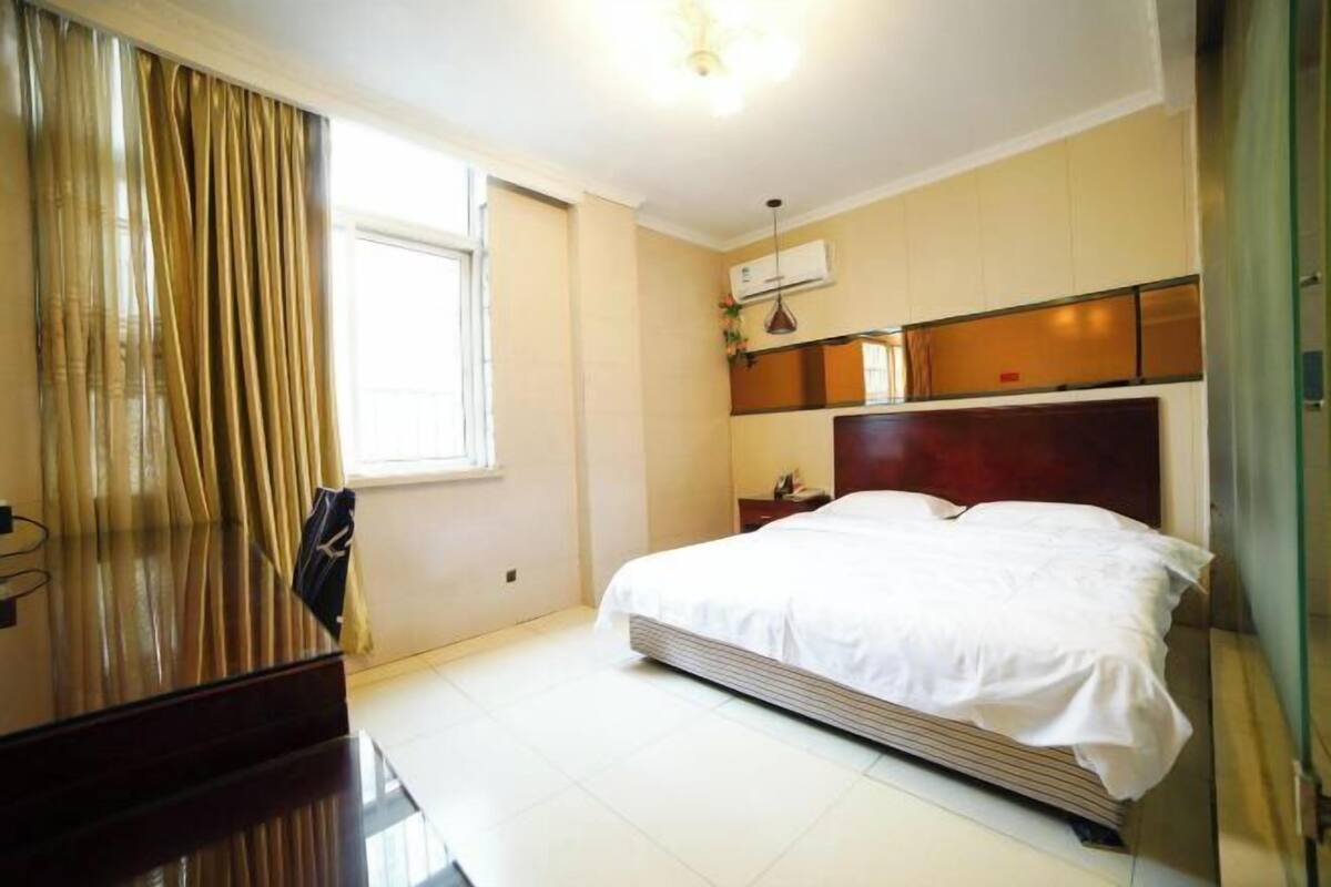 Una habitación de hotel con cama, escritorio y ventana con cortinas.