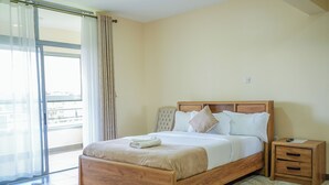Un dormitorio con cama de madera, una mesita de noche y vistas a través de un ventanal grande.