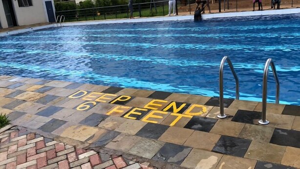 Una piscina con una señalización en el borde que indica 'Zona Profunda 6 Pies'.