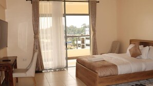 Habitación de hotel con cama, escritorio, silla y vistas al exterior.