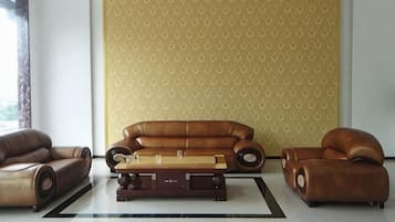 A modern living room with a brown leather sofa, a wooden coffee table, and a patterned wallpaper.