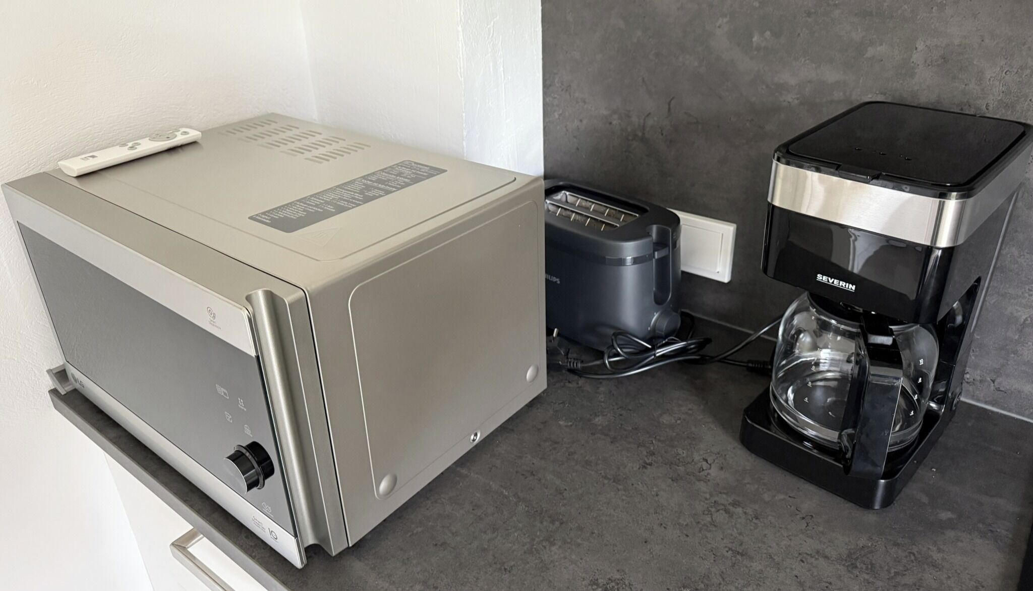 A compact kitchenette with a coffee maker and a small refrigerator.