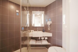 Une salle de bain moderne avec une douche à parois de verre, un lavabo blanc et des toilettes.