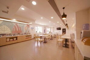 Une cafétéria spacieuse avec de longues tables et des chaises, un espace buffet et un distributeur d’eau.