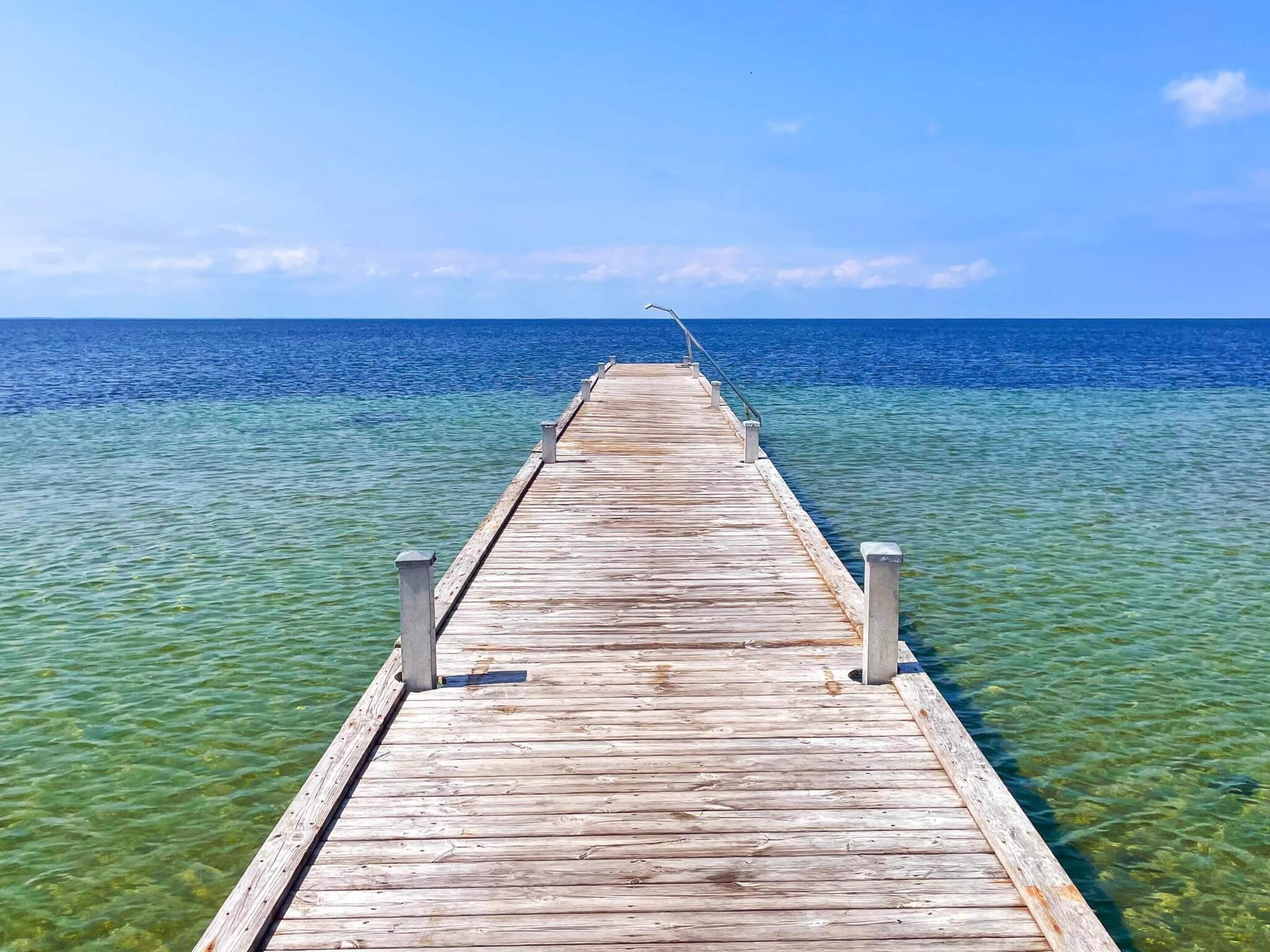 Eine Holzstege in klares, blaues Wasser ragend.