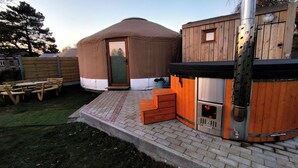 A yurt with a wooden door, a hot tub, and a brick patio.