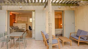 Un patio cubierto con una mesa y sillas, un sofá y un banco de madera.