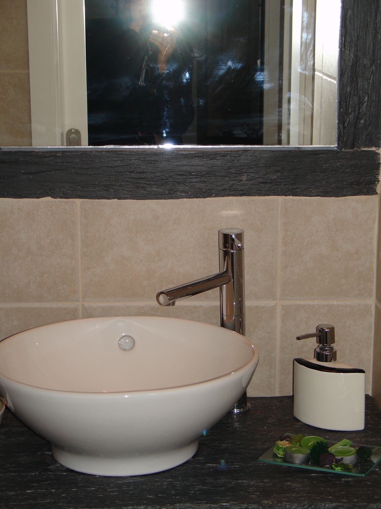 Une salle de bain avec un lavabo blanc, un robinet chromé et un distributeur de savon.
