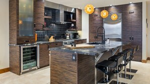 Una cocina moderna con armarios de madera oscura, electrodomésticos de acero inoxidable y una isla central con taburetes de bar.