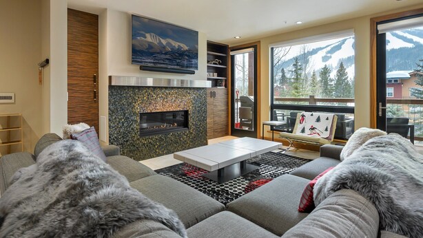 Una sala de estar moderna con chimenea, un ventanal con vistas a la montaña y una zona de estar acogedora.