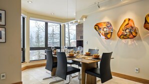 Un comedor moderno con una mesa grande dispuesta para seis comensales, sillas negras y una obra de arte abstracto en la pared.