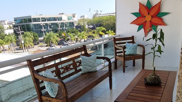 Un balcón con una banca de madera, una mesa y una planta en maceta.