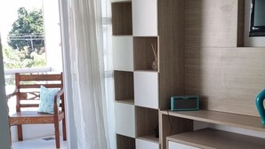 Una sala de estar moderna con un sofá, un televisor, un mueble empotrado y un ventanal corredero que da a un espacio exterior.