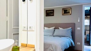 Een slaapkamer met een bed, nachtkastje en een wandplank met een fles.