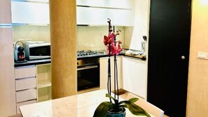 Een kleine keuken met een magnetron, fornuis en kastjes.