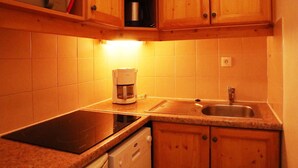 A kitchen with wooden cabinets, a countertop, a coffee maker, a sink, and a dishwasher.