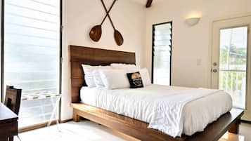 A bedroom with a wooden bed, white bedding, a ceiling fan, and a view of the outdoors.