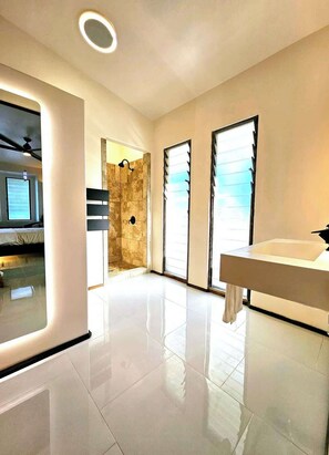 A modern bathroom with a large mirror, a sink, and a shower area.