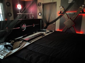 Ein Schlafzimmer mit einem Bett, einem Schminktisch mit Spiegel und Pflegeprodukten sowie einer Wandleuchte.