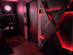 Ein Zimmer mit Hängekorbschaukel, einer Tür mit rundem Griff und einer Wand mit Strukturmuster.