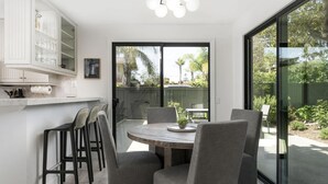 A modern kitchen with a dining area, large windows, and a view of the outdoors.