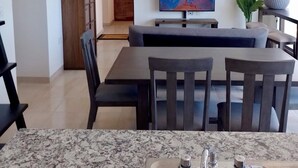 Un soggiorno moderno con zona pranzo, TV a schermo piatto e cucina dotata di piano di lavoro in granito e lavello.