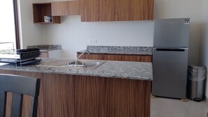 Cucina con mobili in legno, un piano di lavoro in granito, un lavello in acciaio inossidabile e un frigorifero.